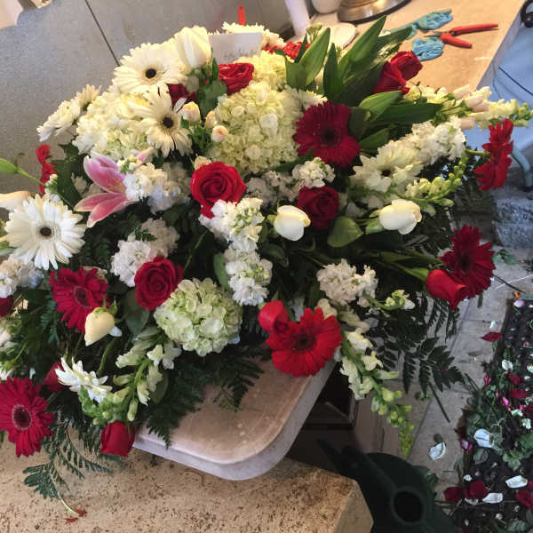 Large floral spray with red roses, white daisies, and lilies
