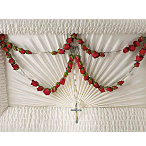 Rosary with red rose buds draped over a white pleated cloth