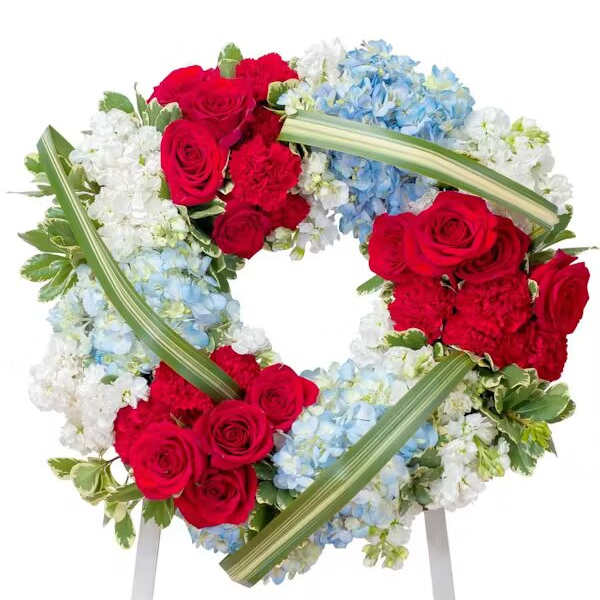 Heart-shaped floral wreath with red roses, blue hydrangeas, and white flowers