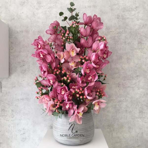 Pink orchid arrangement in a gray ceramic pot