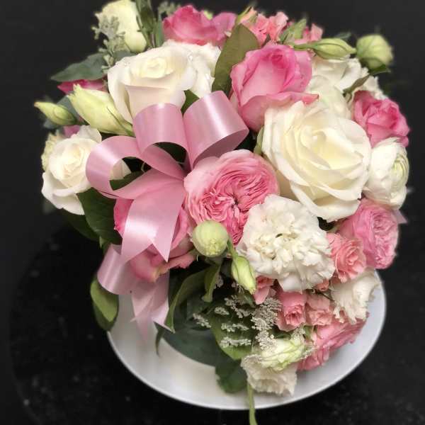 Pink and white rose bouquet with a pink ribbon on a plate