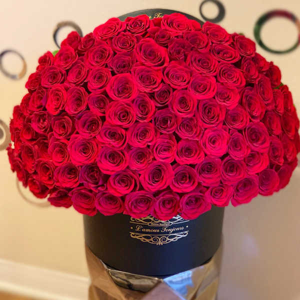 Large dome of red roses arranged tightly in a black hat box