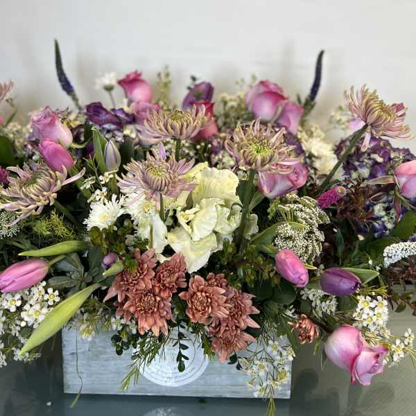 Mixed bouquet of pink and purple flowers in a wooden box