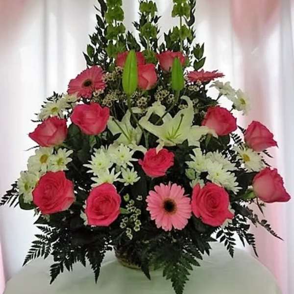 Pink roses, lilies, and daisies arranged in a tall bouquet