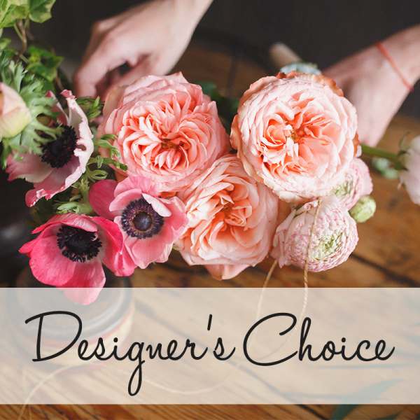 Pink and peach flowers arranged in a bouquet with a designer's choice label