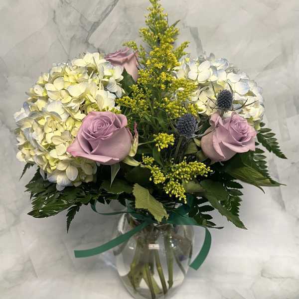 Bouquet of pale hydrangeas and lavender roses in a glass vase