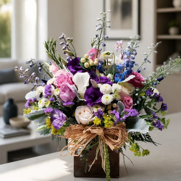 Mixed bouquet of pink, purple, white, and blue flowers in a wooden box