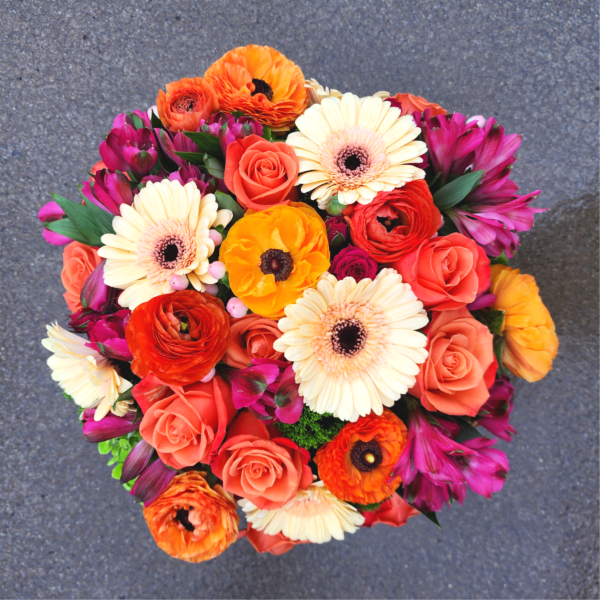 Round bouquet of orange, coral, cream, and magenta flowers