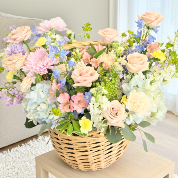 Basket arrangement of pastel roses, hydrangeas, and mixed blooms