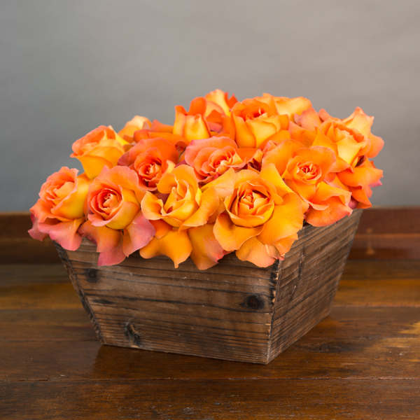 Orange roses arranged in a rustic wooden basket