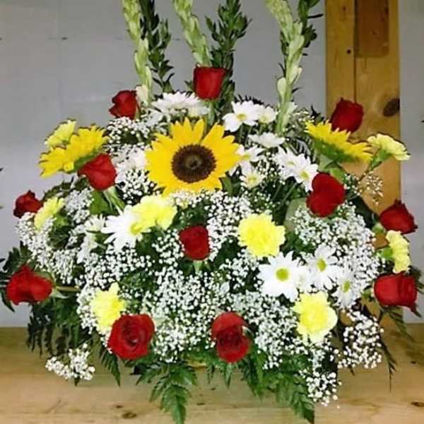 Large funeral spray with red roses, yellow sunflowers, and white daisies