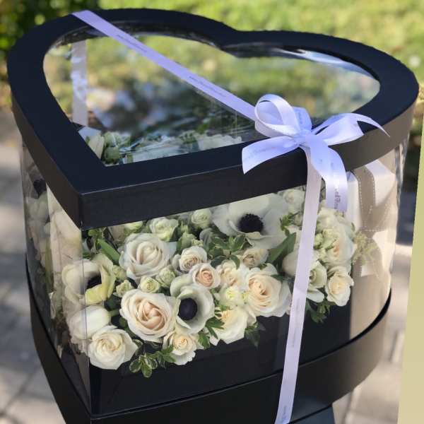 Heart-shaped black box with white roses and a ribbon bow
