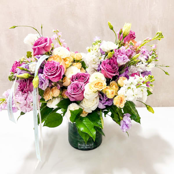 Mixed pink, white, and peach roses in a dark glass vase