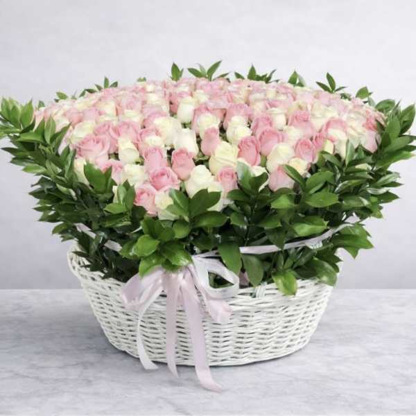 Pink and white roses in a white wicker basket with a ribbon
