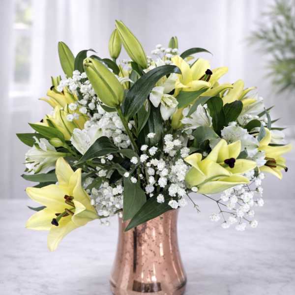Yellow lilies and white baby's breath in a copper vase