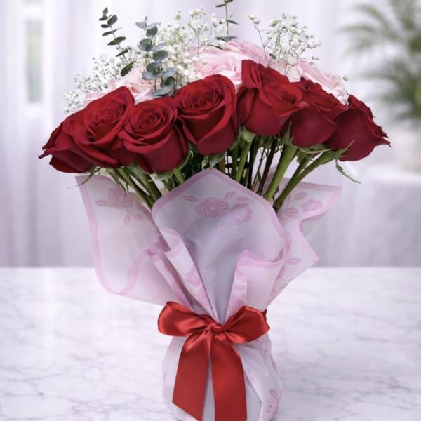 Bouquet of red and pink roses wrapped in pink paper with a red ribbon