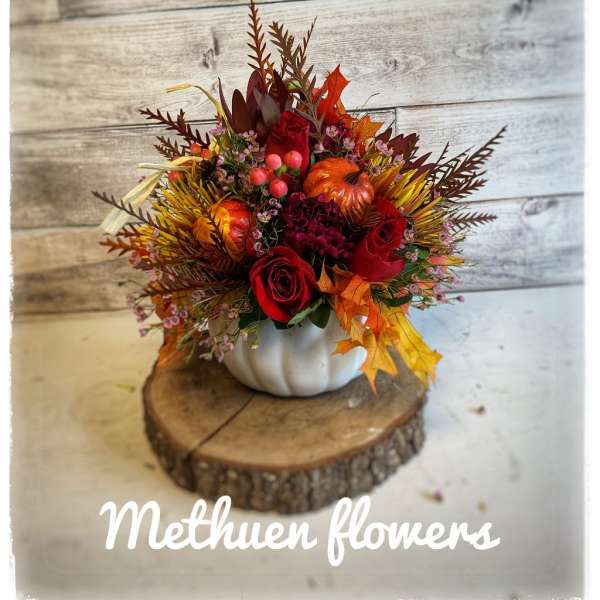 Autumn floral arrangement in a white pumpkin container with red roses and fall leaves