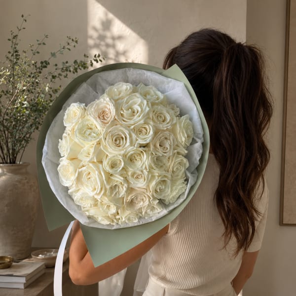 Large bouquet of cream roses wrapped in pale green paper