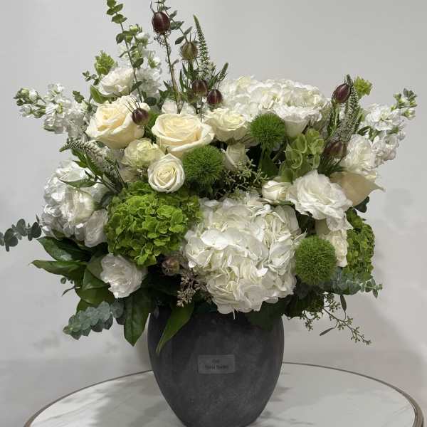 White and green floral arrangement in a dark vase