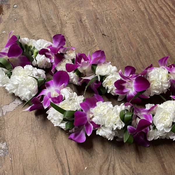 Purple orchid and white carnation floral garlands on a wooden surface