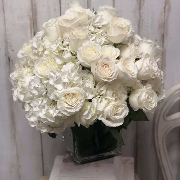 White roses and hydrangeas arranged in a square glass vase