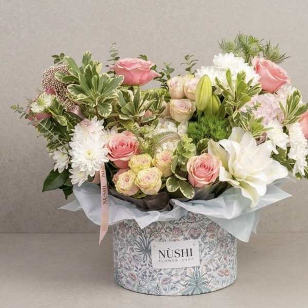 Pink and white flower arrangement in a patterned box
