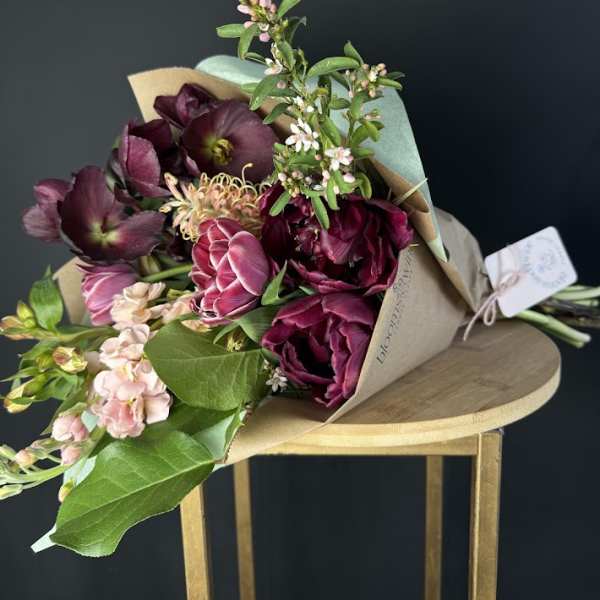 Bouquet of deep burgundy and pink flowers wrapped in kraft paper