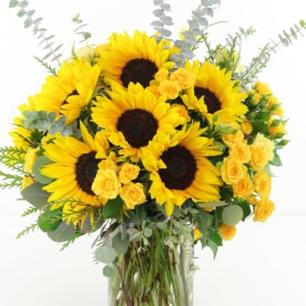 Bouquet of sunflowers and yellow roses in a clear glass vase