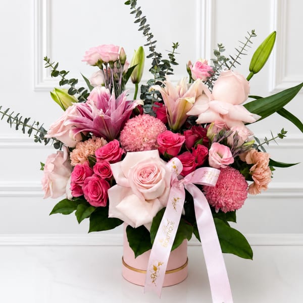 Pink and white mixed flower arrangement in a round box with a ribbon