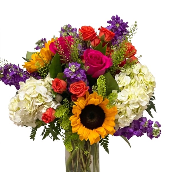 Colorful bouquet with roses, hydrangeas, and a sunflower in a glass vase