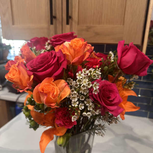 Bouquet of orange and hot pink roses in a clear glass vase