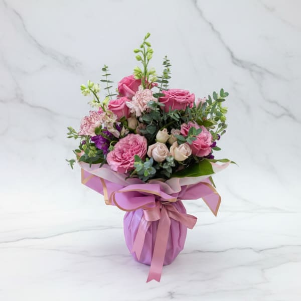 Pink rose bouquet wrapped in lavender paper with a ribbon