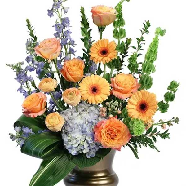 Peach roses and yellow gerbera daisies in a gold vase