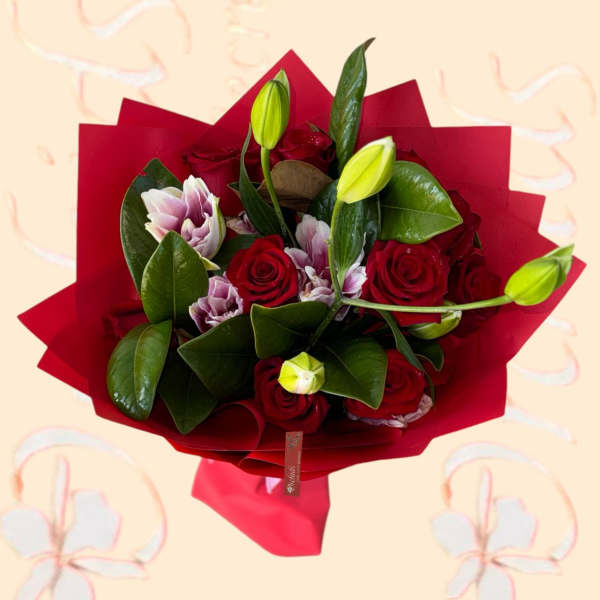 Bouquet of red roses and pale lilies wrapped in red paper