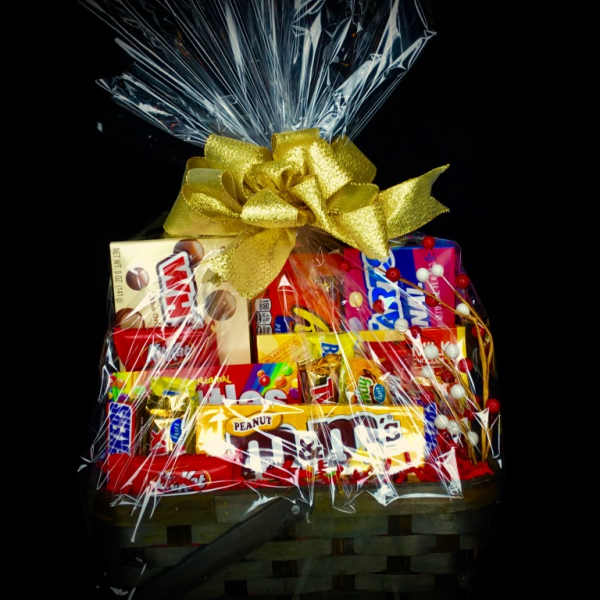 Basket of assorted candy bars wrapped in clear cellophane with a gold bow
