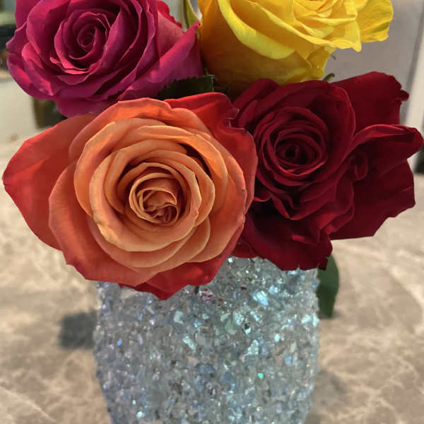 Four roses in a glittery blue vase