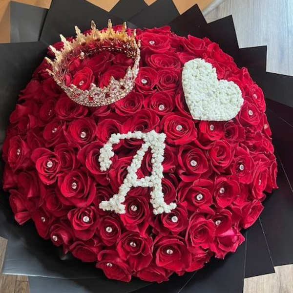 Round bouquet of red roses with a crown and white heart accents