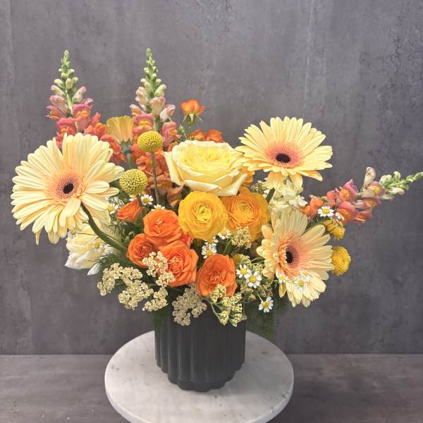 Colorful mixed bouquet in a dark vase with gerberas and roses