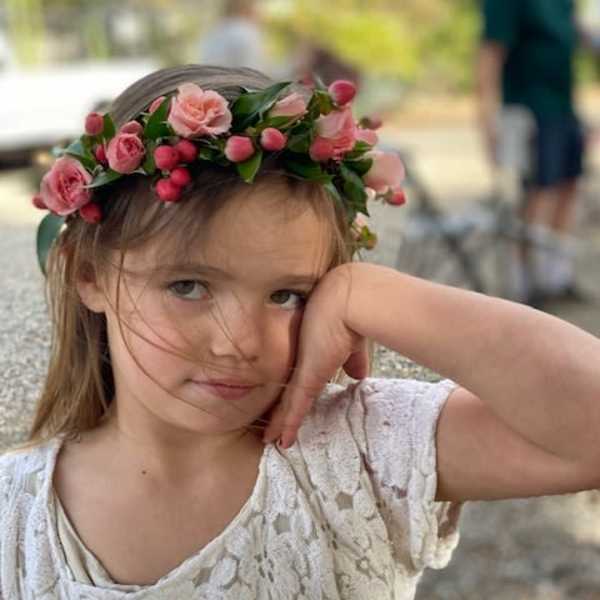 Girl wearing a pink floral crown with small roses and berries