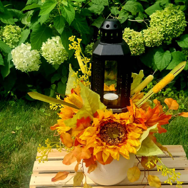Sunflower arrangement in a white pot with a black lantern