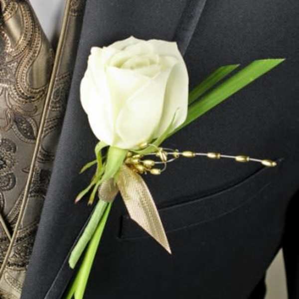 White rose boutonniere with green accents on a dark suit lapel