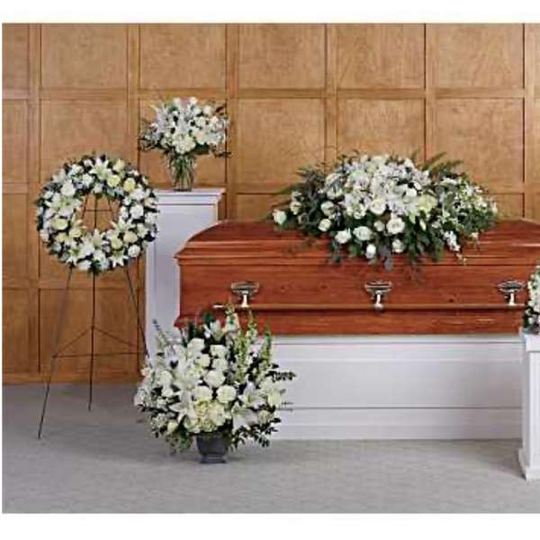 White funeral floral arrangements around a casket in a chapel