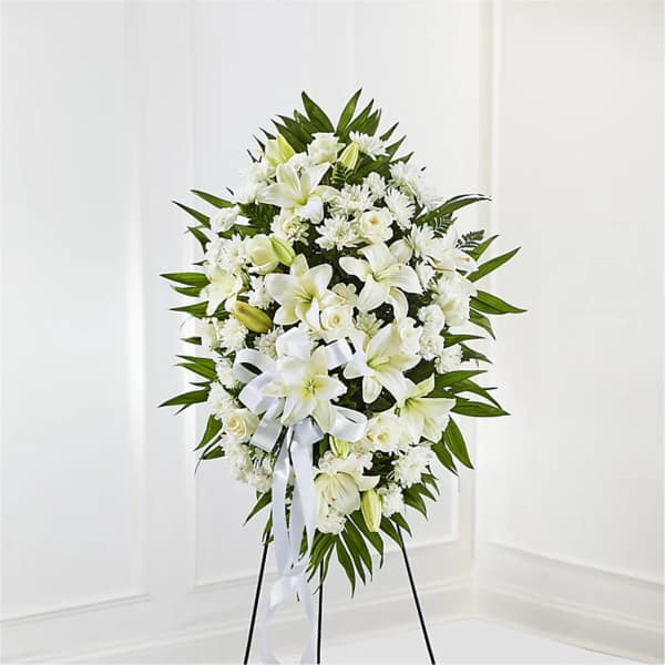 White floral standing spray on a black easel with a ribbon bow