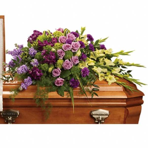 Purple and lavender floral spray on a wooden casket