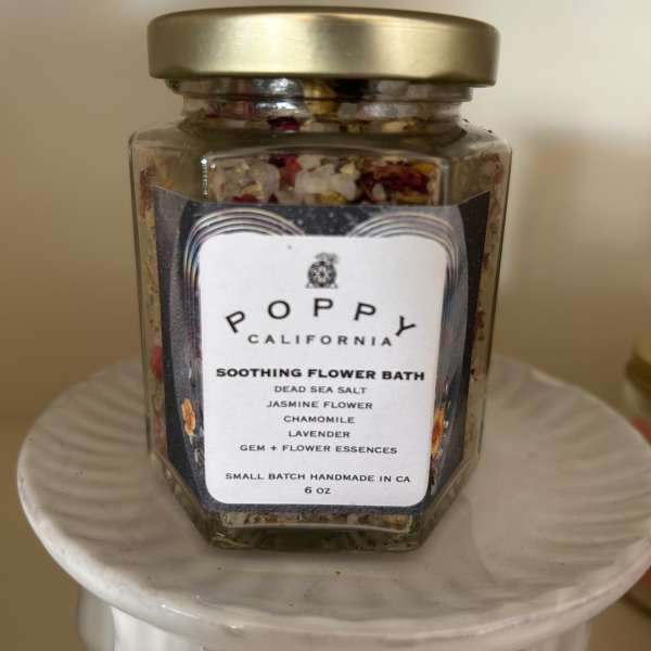Jar of flower bath salts with a gold lid on a white pedestal