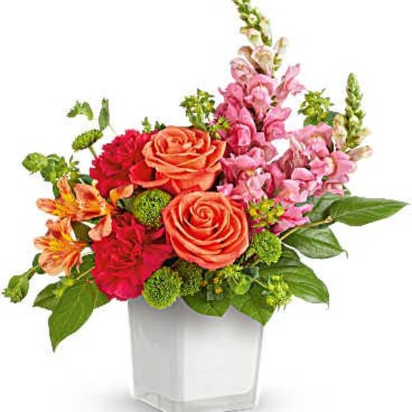 Colorful mixed flower arrangement in a white square vase