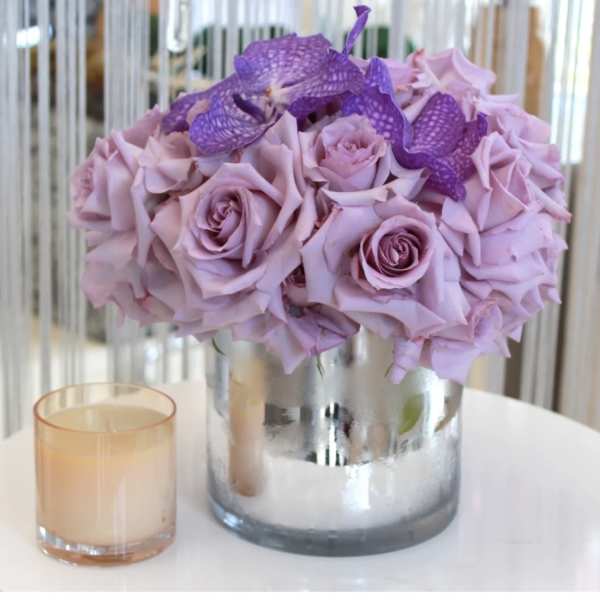 Lavender rose bouquet in a silver vase with a small candle beside it