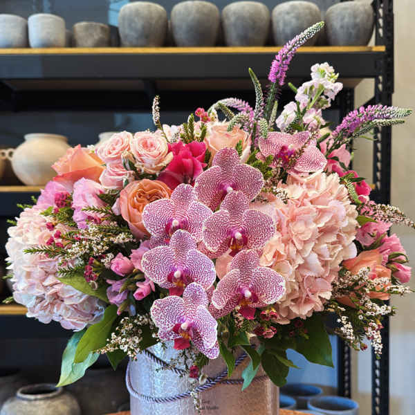 Pink orchid and rose arrangement in a silver hatbox