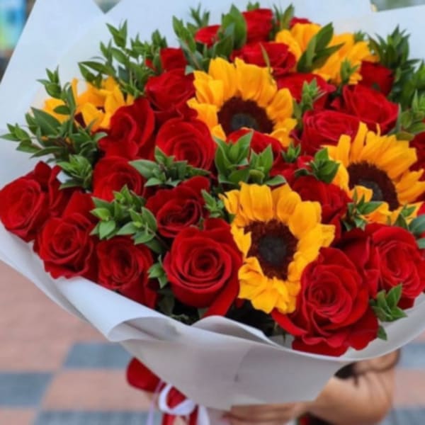 Bouquet of red roses and yellow sunflowers wrapped in white paper