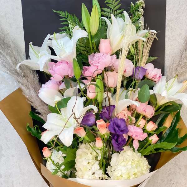 Large bouquet of white lilies, pink and purple flowers, and white hydrangeas